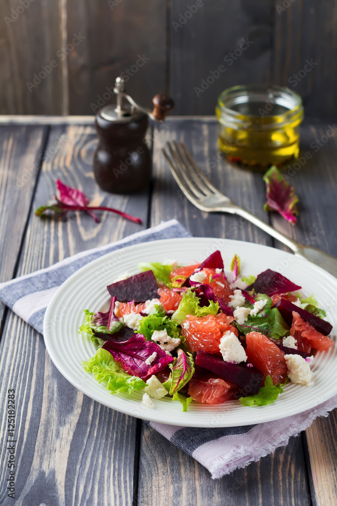 Salad of beets, lettuce, beetroot leaves, grapefruit and feta cheese on the old wooden background. Selective focus. Salad of beets, lettuce, beetroot leaves, grapefruit and feta cheese on the old wooden background. Selective focus.
