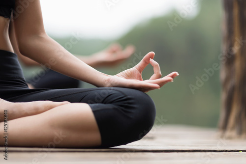 close up hand and soft focus of young people do yoga near the lake