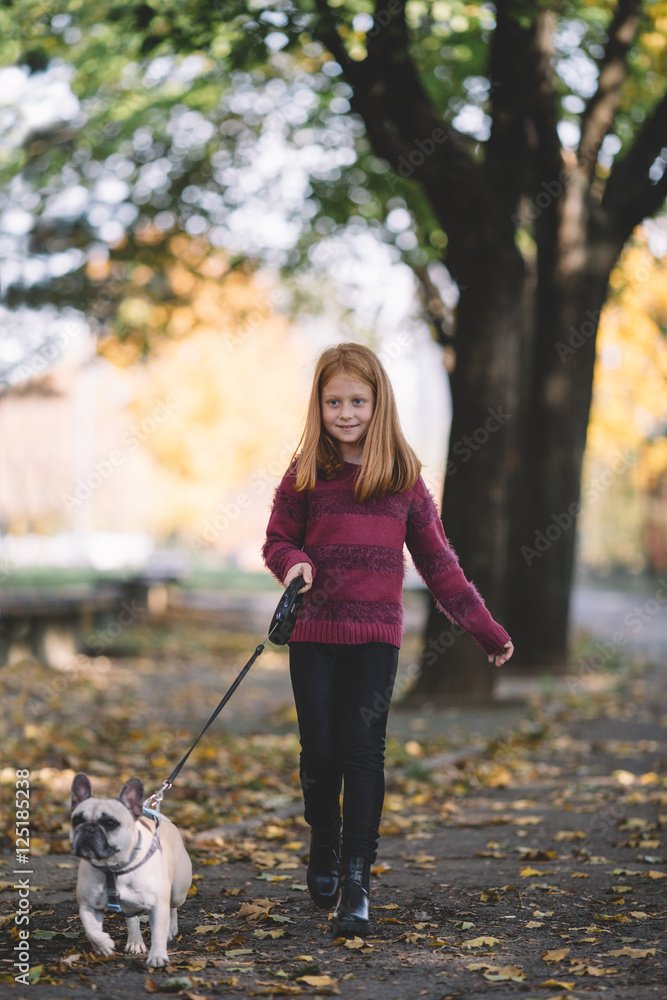 People and dogs outdoors. Beautiful and happy redhead girl enjoying in autumn park walking with her adorable French bulldog. People and dogs outdoors. Beautiful and happy redhead girl enjoying in autumn park walking with her adorable French bulldog.