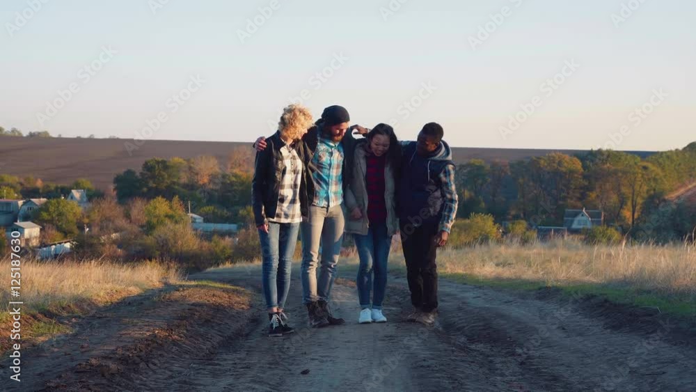 Four multiracial friends walking embraced in line, two of them switching places. Four multiracial friends walking embraced in line, two of them switching places.