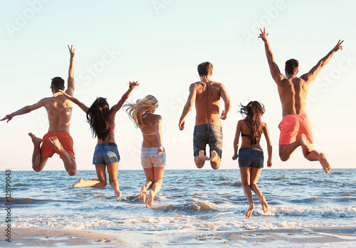 Happy friends jumping on beach