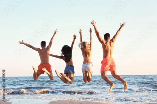 Happy friends jumping on beach