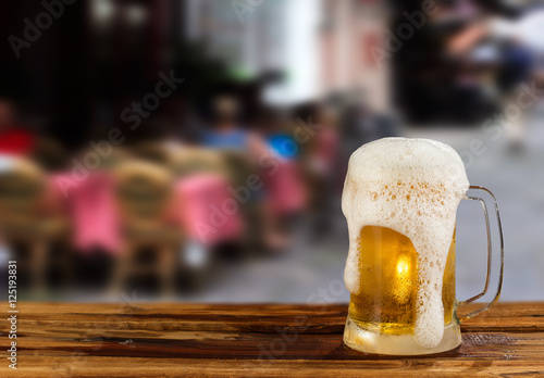 cold mug of beer with foam on the background of the street