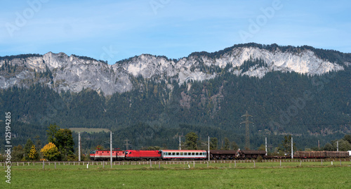 Commercial red train travels to the Austrian Alps.
