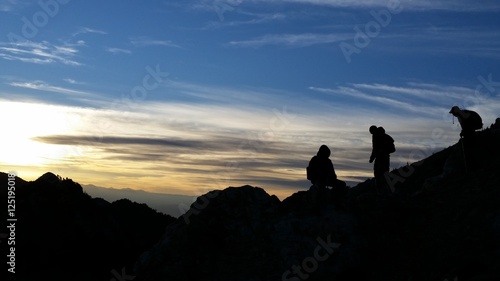 Silhouette of hikers on a ridge in the mountains at sunrise