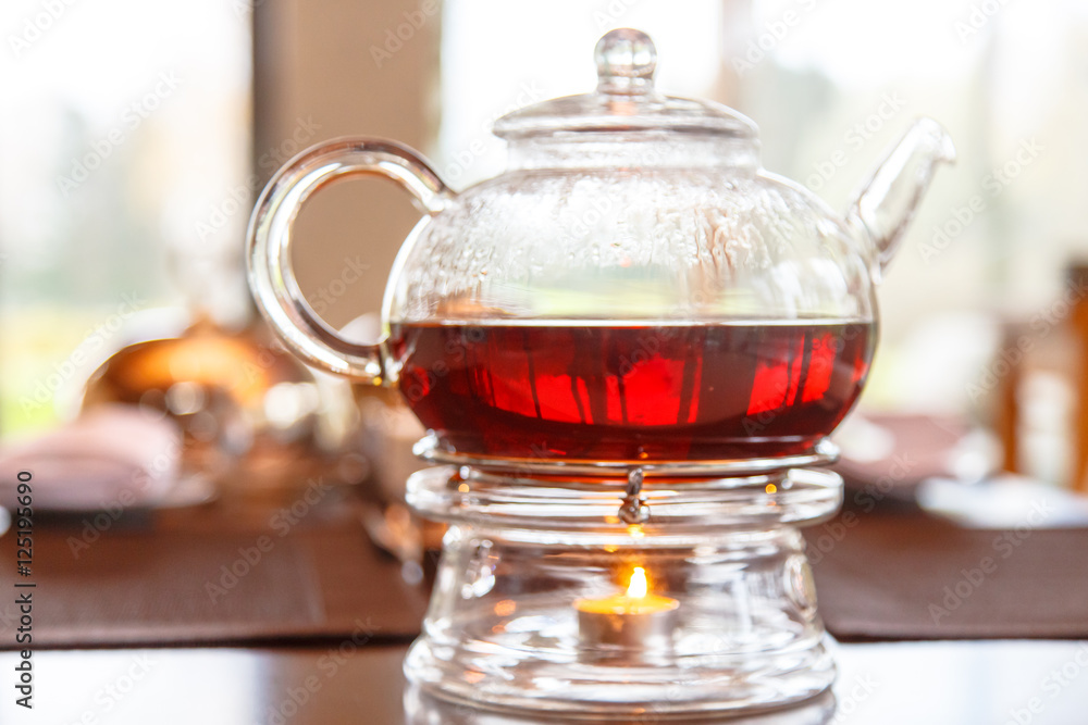 Black tea in glass Cup and glass teapot with a candle stands on Black tea in glass Cup and glass teapot with a candle stands on