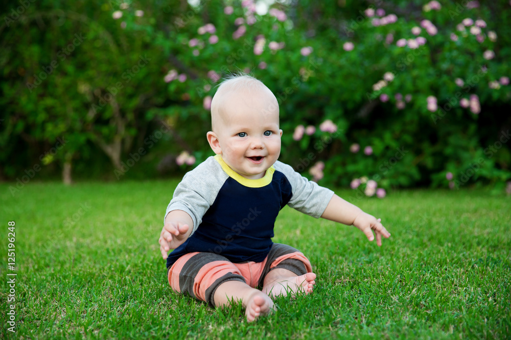 Happy adorable baby boy sitting on the grass Happy adorable baby boy sitting on the grass