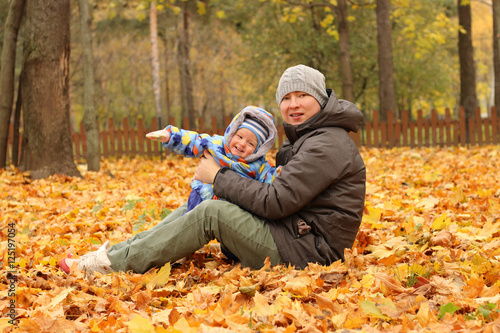 Father and son sitting on fall leaves