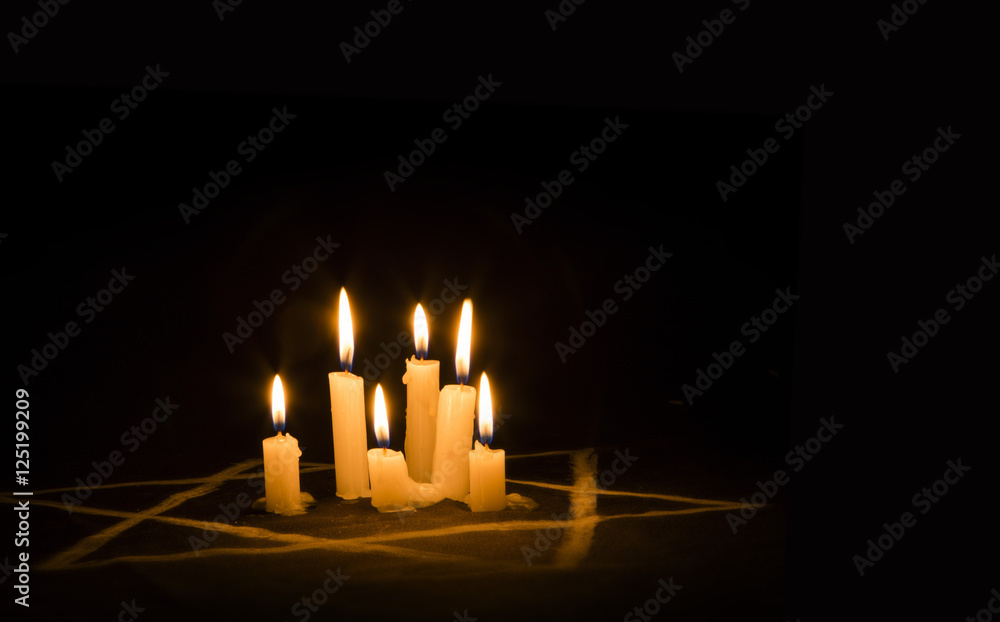 Six burning candles and the Star of David against a black background