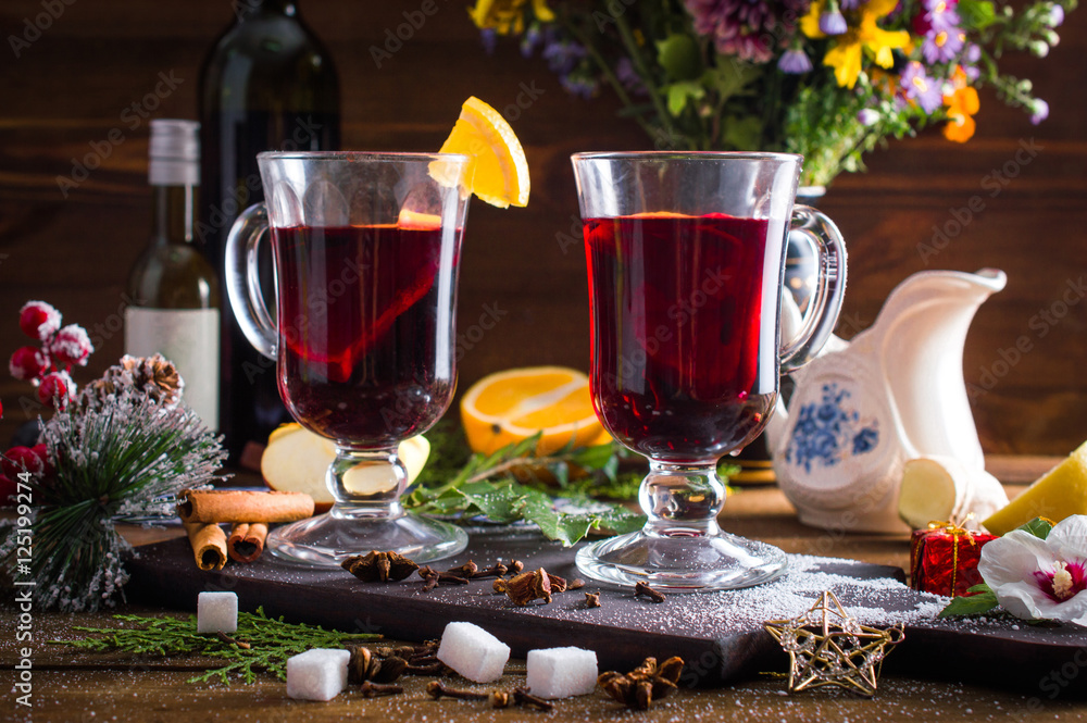 Mulled wine in a cup. Christmas set. Fruits and spices. On a wooden background.