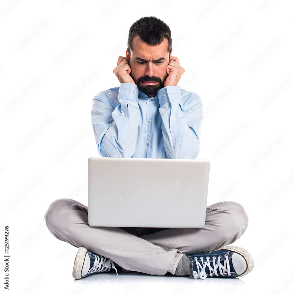 Man with laptop covering his ears Man with laptop covering his ears