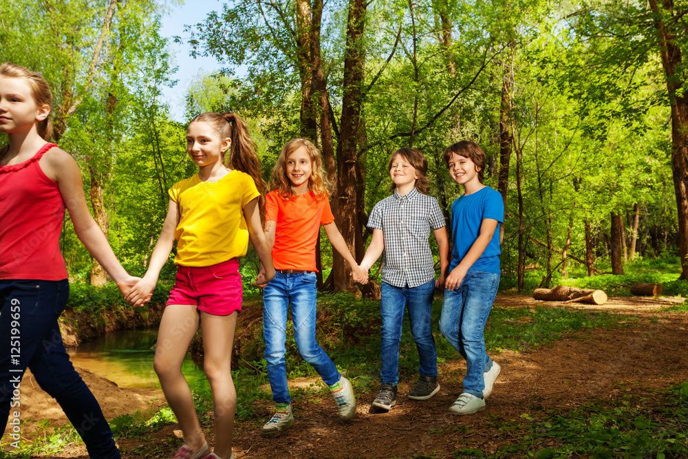 Obraz premium Happy boys and girls walking in the summer forest