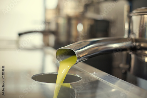 Oil is pouring from the tube at a cold-press factory after the olive harvesting in one of the cretan villages, Greece