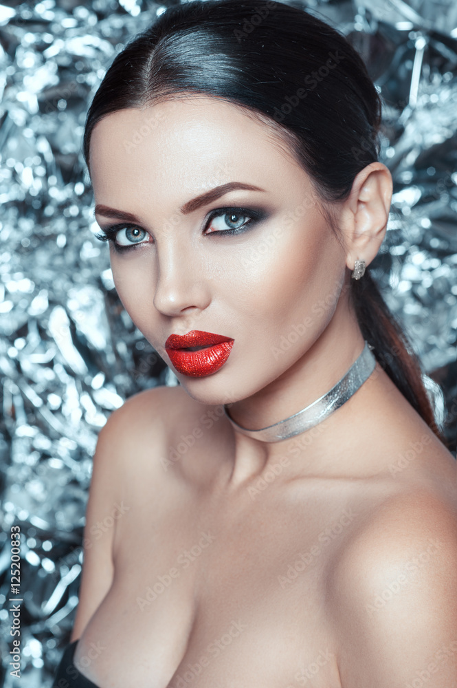 Portrait of beautiful young lady with luxury makeup and stylish accessory on her neck. Holiday makeup on silver bright shiny background. Portrait of beautiful young lady with luxury makeup and stylish accessory on her neck. Holiday makeup on silver bright shiny background.