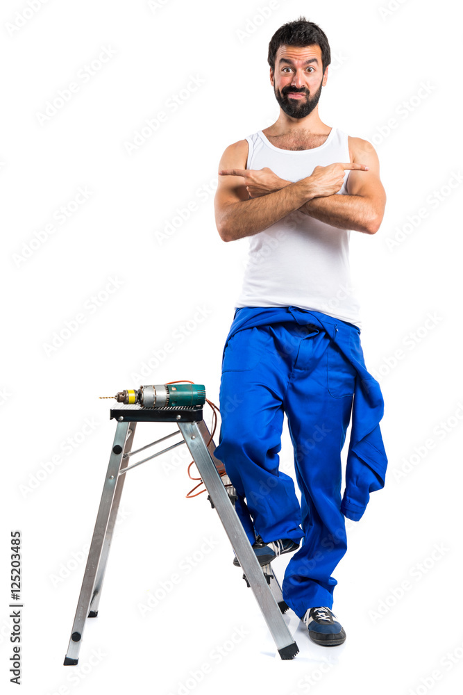 Young electrical technician with a drill pointing to the laterals having doubts Young electrical technician with a drill pointing to the laterals having doubts