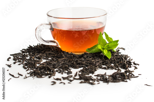 Black tea in a cup of glass. Mint and tea leaves. On white, isolated background.