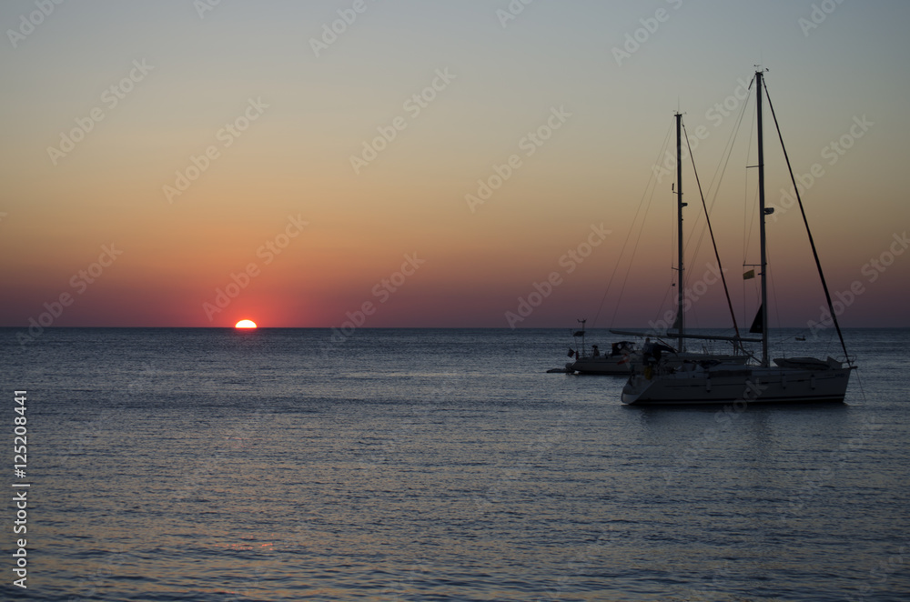 Silhouettes of yachts in the sea at sunset