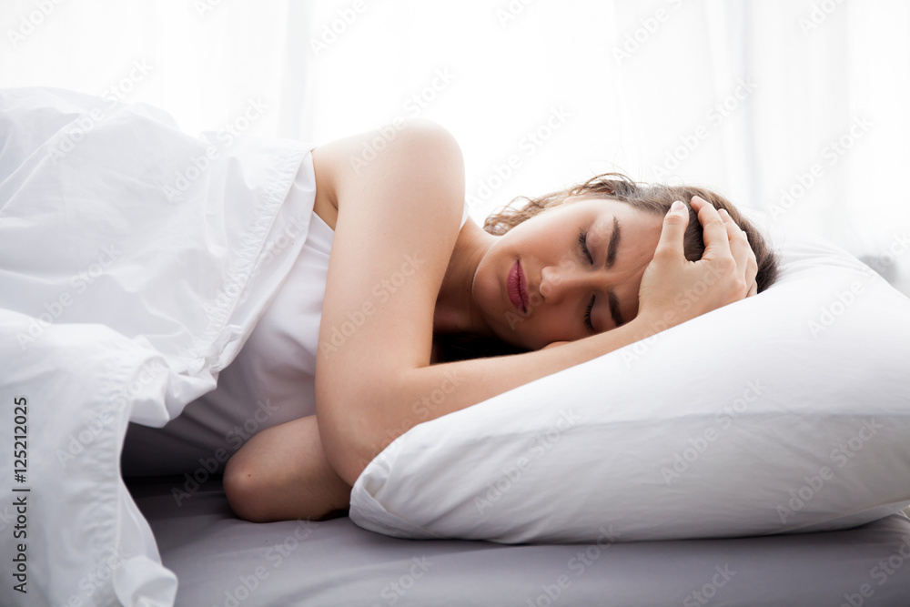 Young beautiful Caucasian woman on bed having headache / insomnia / migraine / stress Young beautiful Caucasian woman on bed having headache / insomnia / migraine / stress