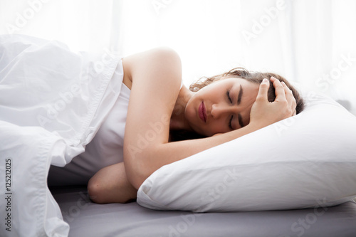 Young beautiful Caucasian woman on bed having headache / insomnia / migraine / stress