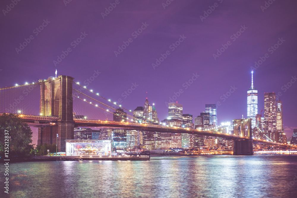 New York City skyline and Brooklyn Bridge at night with light and vintage toned filter effect