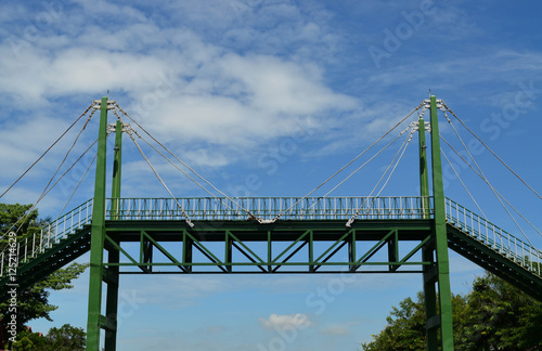 Green sling iron bridge over blue sky