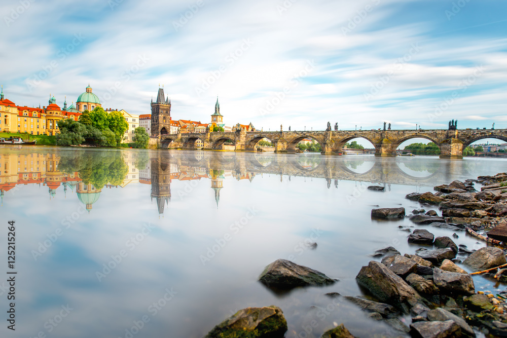 Citycsape view on the riverside with the bridge and old town in Prague. Long exposure image technic with glossy water