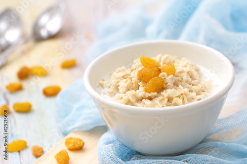 Porridge with raisin and honey in white bowl for breakfast