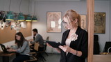 4k. young beautiful blonde businesswoman uses a touchscreen tablet in the modern startup office.