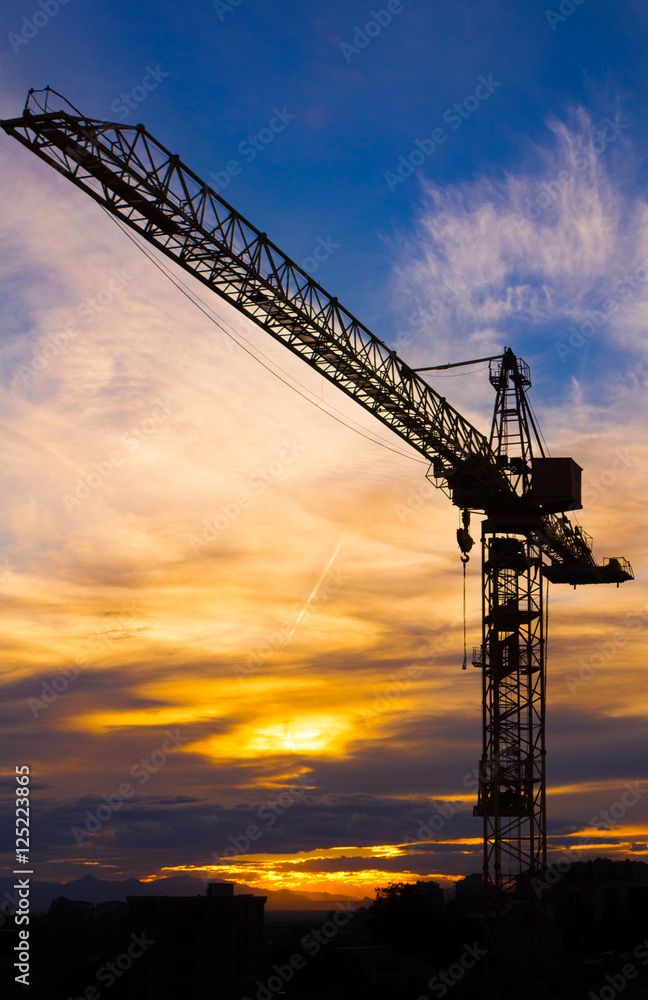 Crane silhouetted against the sunset with orange clouds
