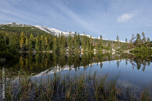 Fototapeta Naklejka Na Ścianę i Meble -  Reflections in the calm lake water with snow and mountains