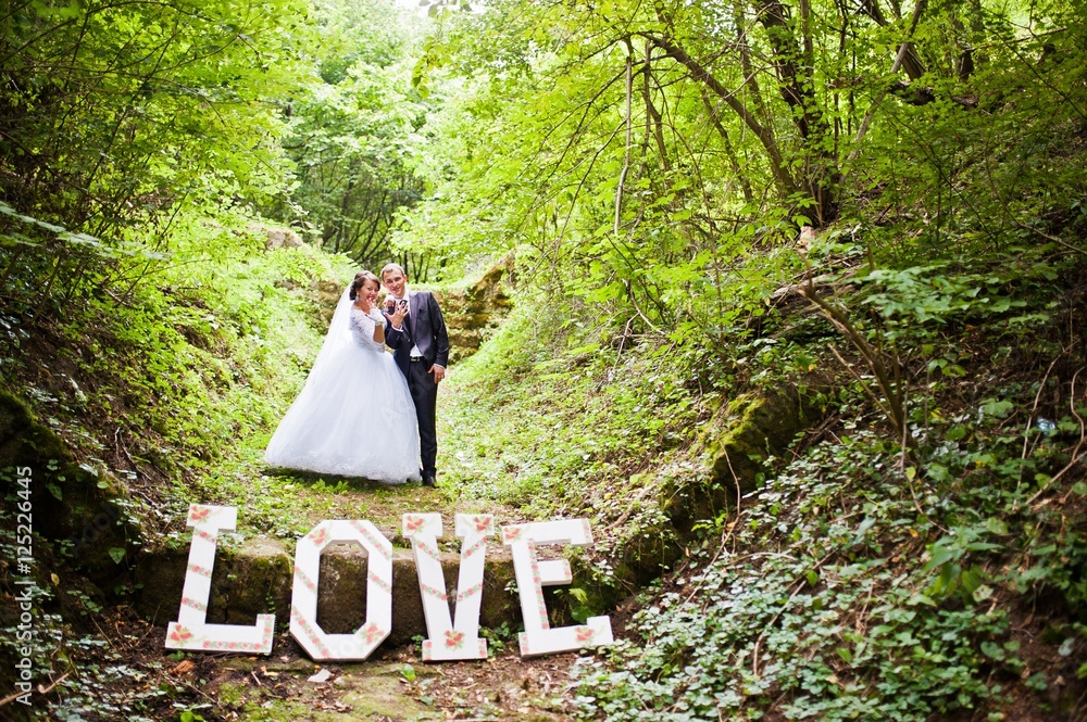 Wedding couple at green alley with big word love Wedding couple at green alley with big word love
