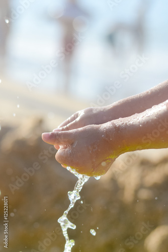 Happy child holding hands in water. Summer outdoors background