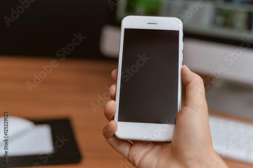 Top side view of a business person hands using smart phone, office desk background
