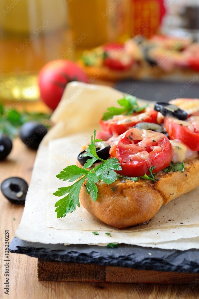 gratinated baguette with ham, olives, tomatoes,cheese