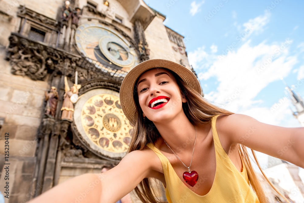 Fototapeta premium Młoda turystka robi autoportret przed słynnym zegarem astronomicznym w Pradze