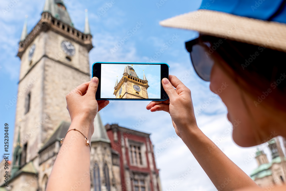 Fototapeta premium Woman photographing with smart phone the clock tower in Prague city