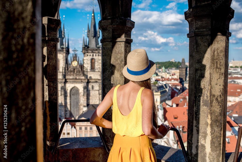 Fototapeta premium Young female tourist enjoying great view on the old town of Prague from the top of the clock tower