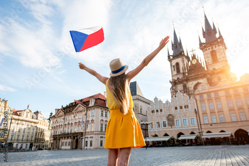 Young female tourist dressed in yellow holding czech flag on the old town square of Prague. Enjoying great vacation in Czech republic photo