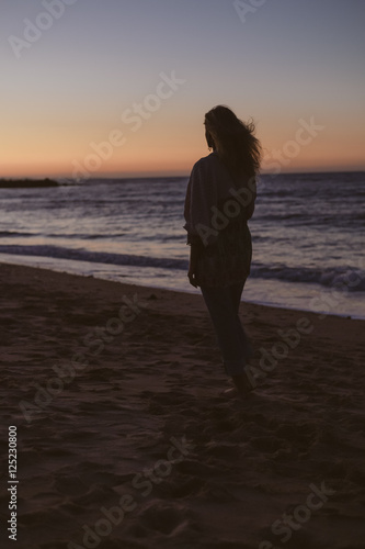 Silhouette of woman on the ocean beach. Natural summer beautiful sunset background © aquar