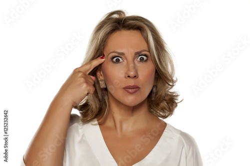 beautiful middle-aged woman with a questionable gesture and her finger to her forehead