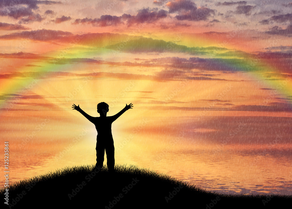 Happy child standing beside sea on hill sunset sky and rainbow