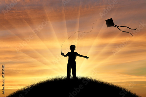 Boy playing with kite on sunset © Prazis Images