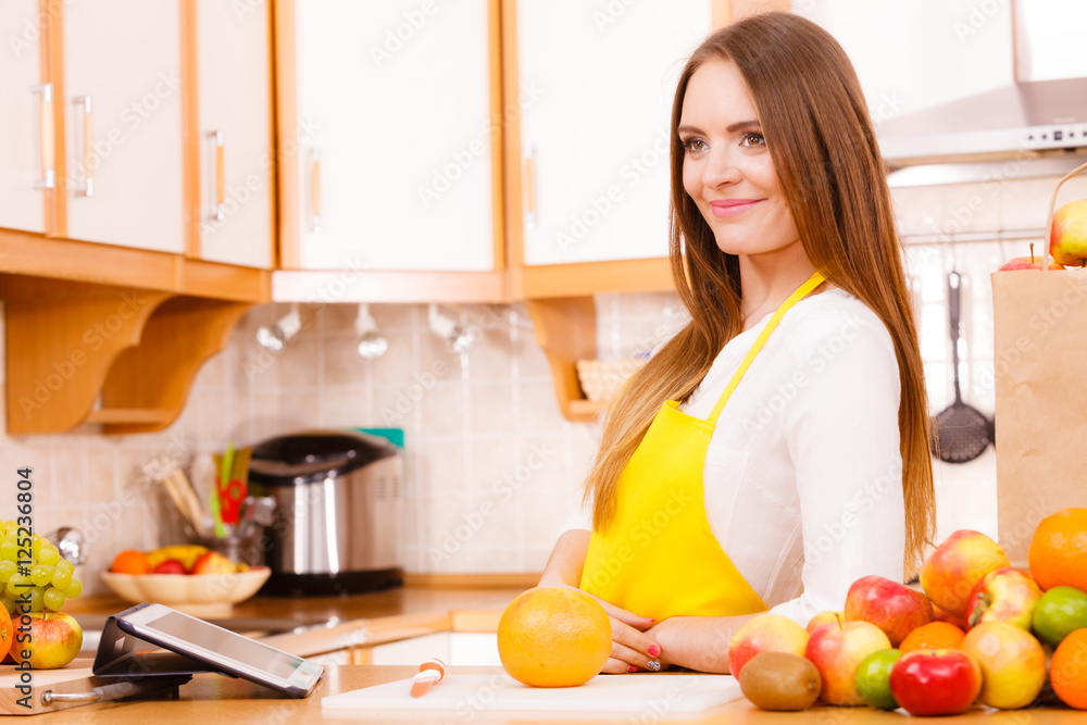 Woman housewife in kitchen using tablet