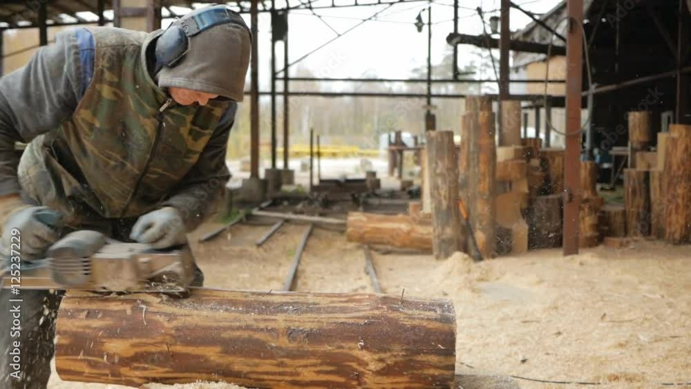 Construction worker planing a piece of wood for a building project. Construction grinds electric hand plane. Against the background of the factory premises, slow motion Construction worker planing a piece of wood for a building project. Construction grinds electric hand plane. Against the background of the factory premises, slow motion