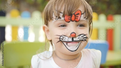 Little girl get painted face as a cat for a carnival