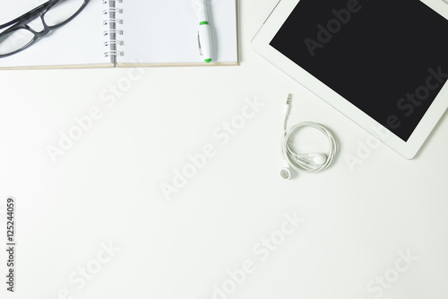 Top view white desk with leye glasses, smart phone, pen note b