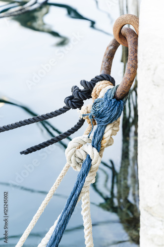 nodes and ropes, details of colored ropes knotted to a rusted metal ring