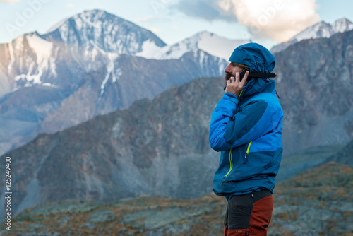 man talking on a satellite phone in the mountains photo