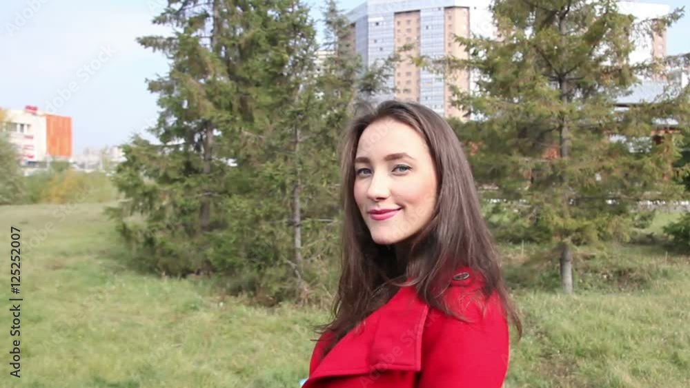 Beautiful girl in a red coat and is smiling at the camera Beautiful girl in a red coat and is smiling at the camera