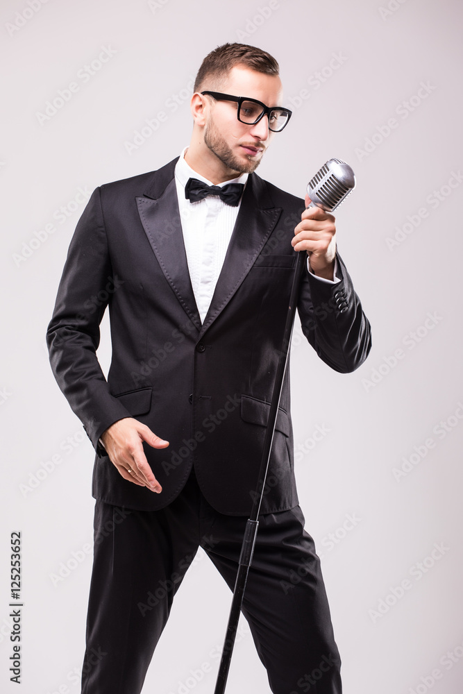 Naklejka premium Young man in suit singing over the microphone with energy. Isolated on white background. Singer concept.